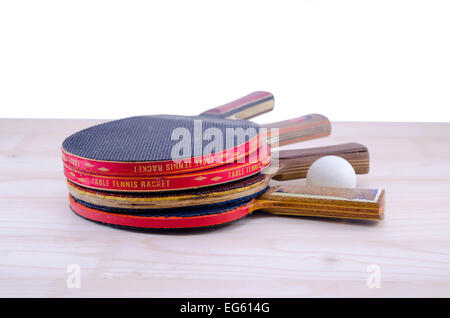 Bunch of old table tennis rackets and a ping pong ball on a table isolated Stock Photo