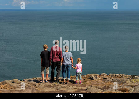 Family, father, mother with son and little daughter looking from cliff top over the sea Stock Photo