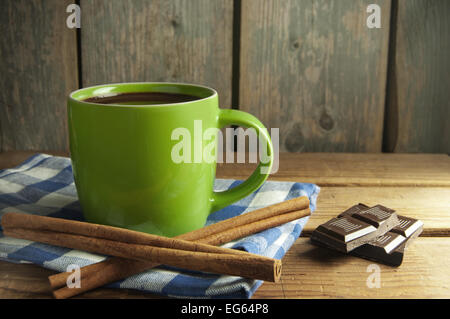 Hot drink in a cup with blocks of chocolate and cinnamon sticks on one side Stock Photo