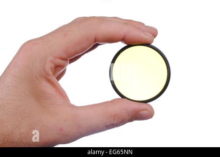 man hand holds a yellow photographic filter, isolated on white background Stock Photo