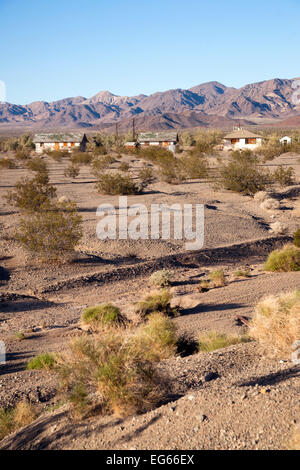 Dry ground and sage brush inhabit the foreground with abandoned buildings in the background Stock Photo