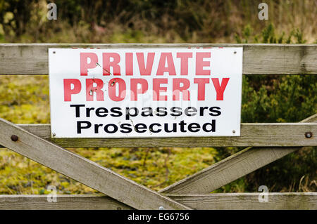 Sign on a wooden gate advising public that this is private property and trespassers will be prosecuted Stock Photo