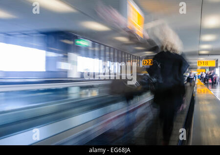 People on a moving walkway at an airport, blurred to show movement and speed. Stock Photo