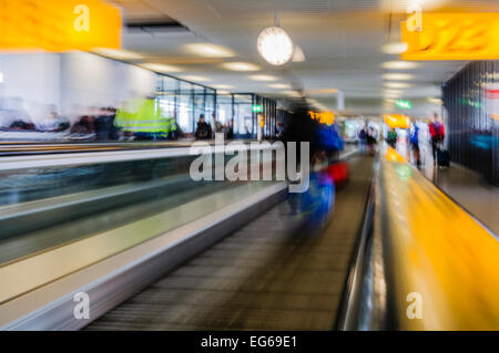 People on a moving walkway at an airport, blurred to show movement and speed. Stock Photo