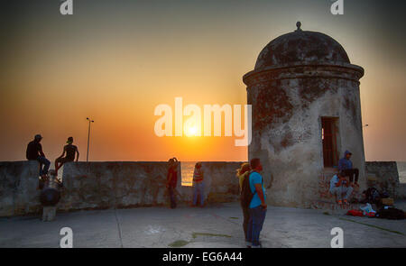 Cartagena, Colombia - February 24, 2014 - Tourists and local residents watch the sun set over the caribbean sea from the old cit Stock Photo