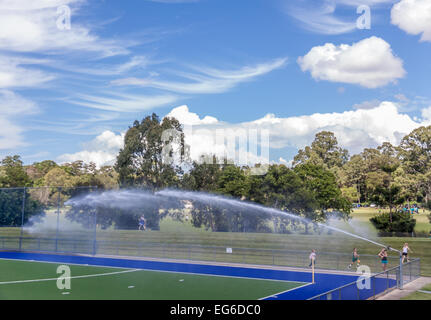 Watering artificial grass  hockey ground. Stock Photo