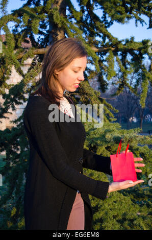 Brunette finding her Valentine's gift on a tree in a park Stock Photo