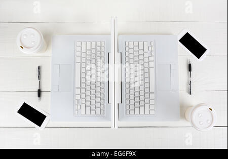 High angle shot of two laptop work stations back-to-back with mirror image identical layouts. Horizontal format on a white wood Stock Photo