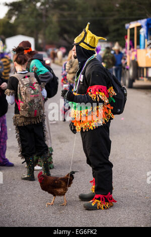 A reveler wearing traditional Cajun Mardi Gras costume walks a chicken on a leash during the Courir de Mardi Gras chicken run on Fat Tuesday February 17, 2015 in Eunice, Louisiana. Cajun Mardi Gras involves costumed revelers competing to catch a live chicken as they move from house to house throughout the rural community. Stock Photo