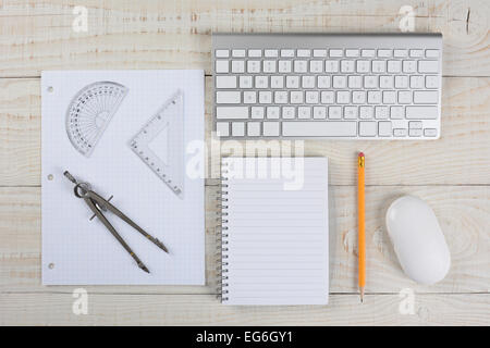 Overhead shot of a computer keyboard and mouse next to a sheet of graph paper, a compass and protractor, on a whitewashed wood t Stock Photo