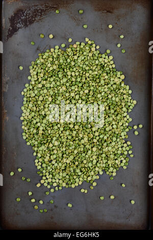 High angle shot of a pile of green split peas on a well used metal baking sheet. Vertical Format. Stock Photo