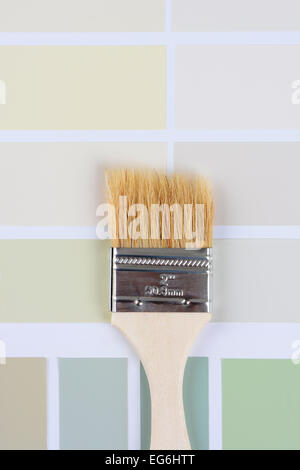 High angle closeup shot of a paint brush laying on a color sample chart. Vertical format. Stock Photo