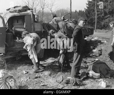 Civilians loot a knocked out German vehicle loaded with clothing and food. March 28, 1945 near Herborn, Germany. World War 2. Stock Photo