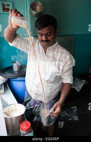 'Chai wallah' or tea maker - tea man pours his chai between glasses before serving to customers, Kumily, Kerala, Southern India Stock Photo