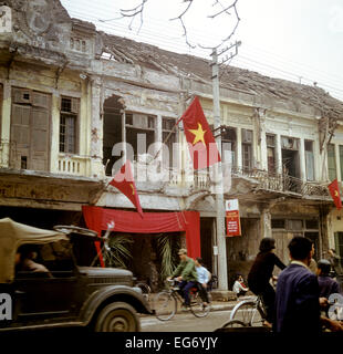Red flags on a war-destroyed house at a street in Hanoi in North Vietnam, photographed in March 1973. The United States of America flew about 2,000 air attacks on cities and targets in North Vietnam during the 'Christmas bombings' in 1972. The peace agreement was signed on the 27th of January in 1973 in Paris. Inhabitants dig out reusable bricks out of ruins. Photo: Werner Schulze Stock Photo