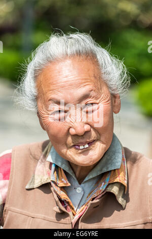 Shanghai, China - April 7, 2013: old chinese woman friendly toothless toothy smiling outddors portrait at the city of Shanghai in China on april 7th, 2013 Stock Photo