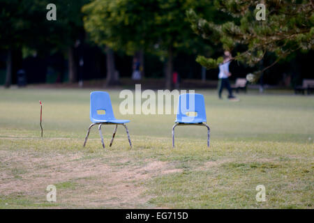 Two small blue plastic seats on putting golf course Stock Photo