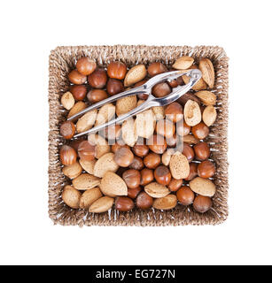 Mixed nuts in a woven basket with nut cracker, isolated on white Stock Photo