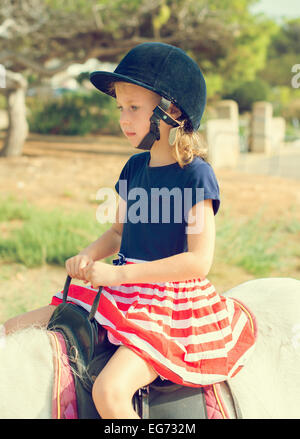 Portrait of little girl riding pony. Stock Photo