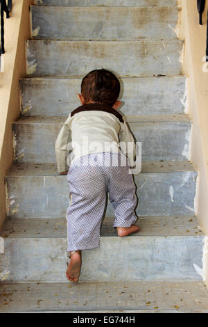 Young baby boy attempting to ascend steps of staircase Stock Photo