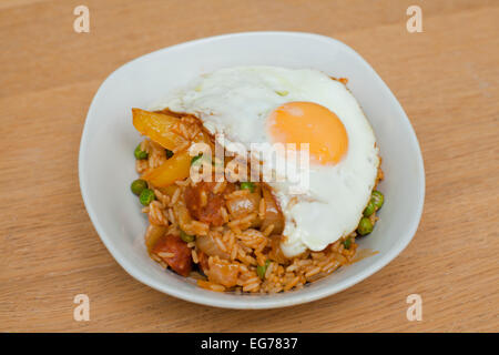 Cajun-style rice dish with chorizo, peppers and peas, topped with a fried egg. Stock Photo