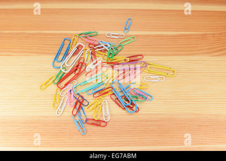 Large and small coloured paper clips on a wooden background Stock Photo