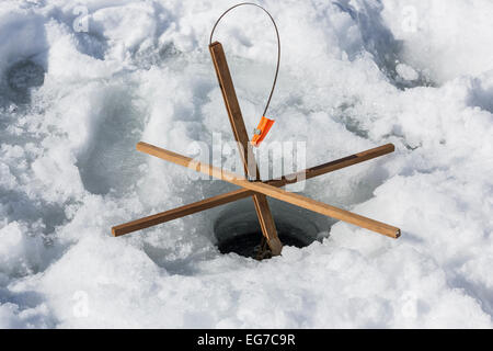 Hand ice auger and tip-up ice fishing rod at frozen lake at Winter