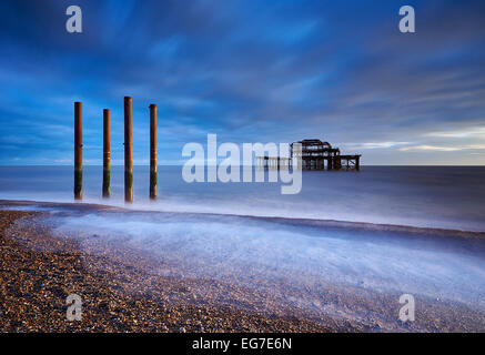 The decaying remains of Brighton's West Pier at sunset with the tide coming in.