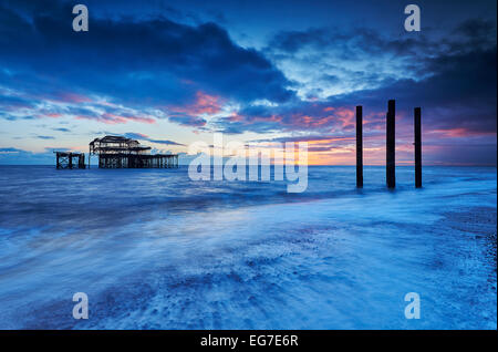 The decaying remains of Brighton's West Pier at sunset with the tide coming in.