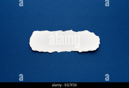 Piece of torn paper on a blue background. Space for text. Stock Photo