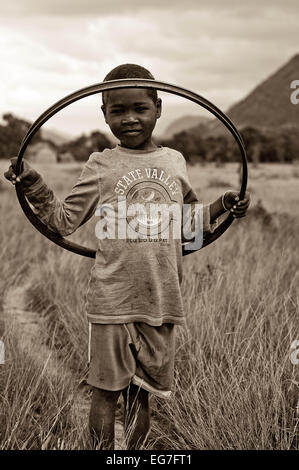 A young boy plays with an inner wheel from a bicycle in the scrub lands of South East Madagascar Stock Photo