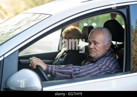 older driver in the car using smartphone, female passenger sitting in the car Stock Photo