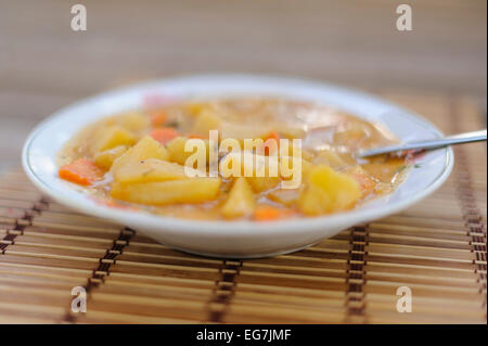 Pumpkin soup in a white traditional decorated plate on bamboo background. Stock Photo