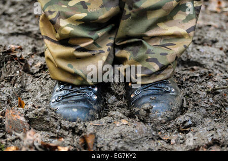 A soldier wearing boots and camouflage uniform stands in deep mud Stock Photo