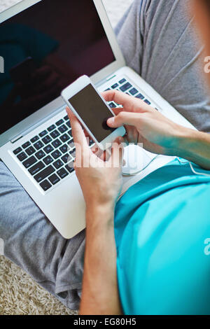 Young man using cellphone and laptop Stock Photo