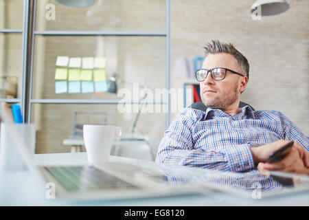 Calm businessman in eyeglasses sitting in office Stock Photo