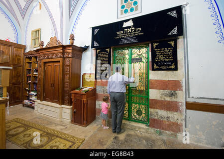 A jewish man and a girl are watching through the bars of a iron door to the tomb of Leah, wife of Jacob Stock Photo