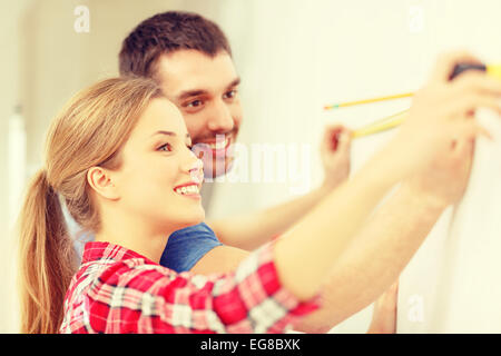 smiling couple measuring wall Stock Photo