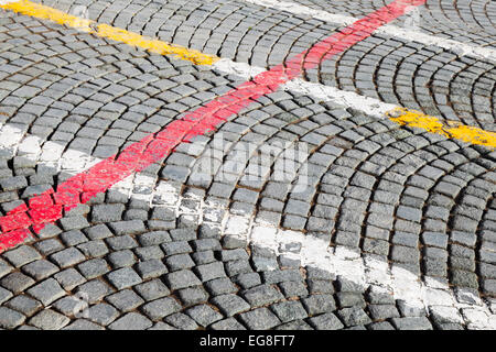 White, red and yellow road marking lines over on gray cobblestone pavement, abstract urban background Stock Photo