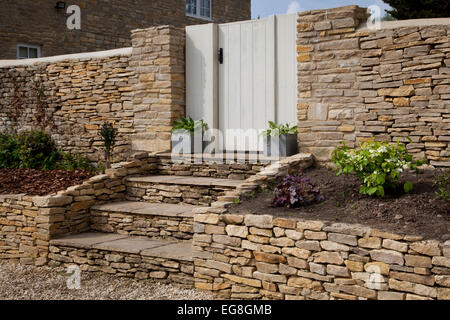 Dry stone wall and steps with gateway into English garden,Oxfordshire,England Stock Photo
