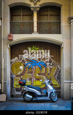 motor scooter in front of graffitied doorway Barcelona Spain Stock Photo