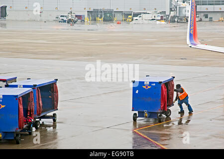 Chicago, Illinois - A member of the Southwest Airlines ground crew pushes a luggage cart on the tarmac at Midway Airport. Stock Photo