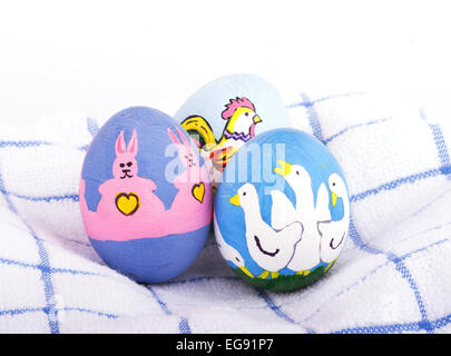 Bright colored hand painted Easter eggs with cute animals on a soft white and blue towel Stock Photo