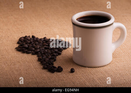 Coffee cup with beans in shape of South America on burlap, with a light vignette Stock Photo