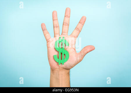 Hand up showing/catching a green dollar symbol with blue background. Stock Photo