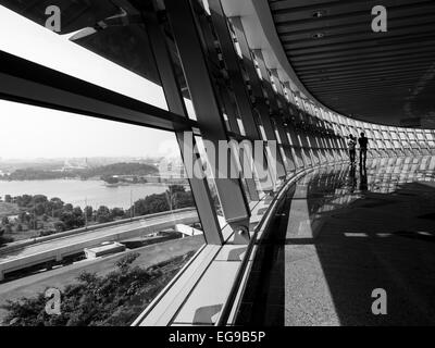 Two men walking along glass walls overlooking a park Stock Photo