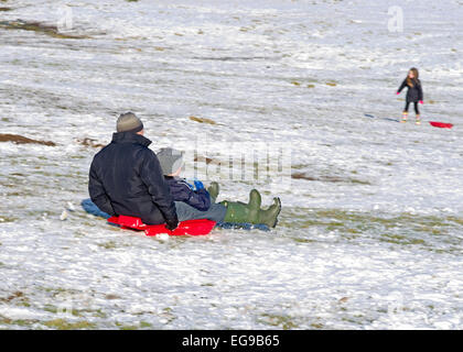 Man and boy on sledge together sledging downhill on snowy hillside Caldbeck fells, Lake District, Cumbria, England UK Stock Photo