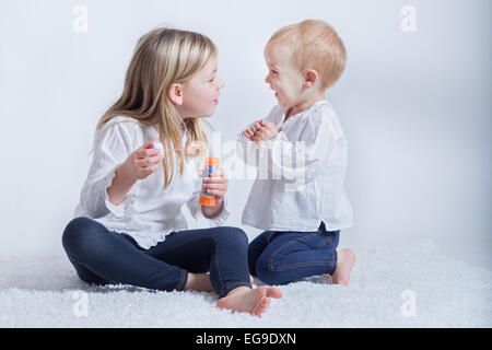 Two children playing with a bubble wand Stock Photo