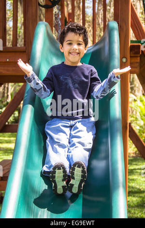 Boy in playground sliding down a slide Stock Photo