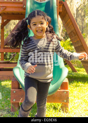 Happy girl getting off slide Stock Photo